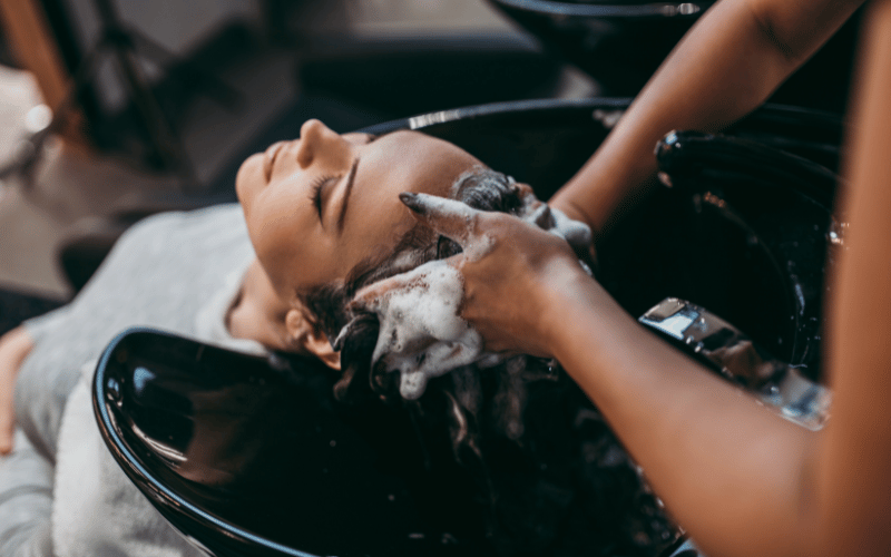 Professional hair care in action at our hair salon in Palm Beach Gardens, showcasing a stylist's hands as they expertly massage shampoo into a client's scalp.