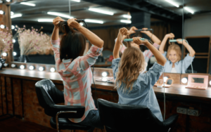 A candid shot of a mother and her daughter engaging in hair-styling fun, capturing the essence of a family-friendly haircut experience in Palm Beach Gardens.