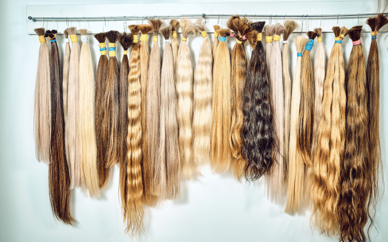 A display of aqua hair extensions in Palm Beach Gardens with various hair colors and textures available for styling.