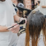 Professional stylist applying hair dye during a hair coloring service. This treatment showcases modern hair color ideas in 2024, with a focus on trendy new shades for the season.