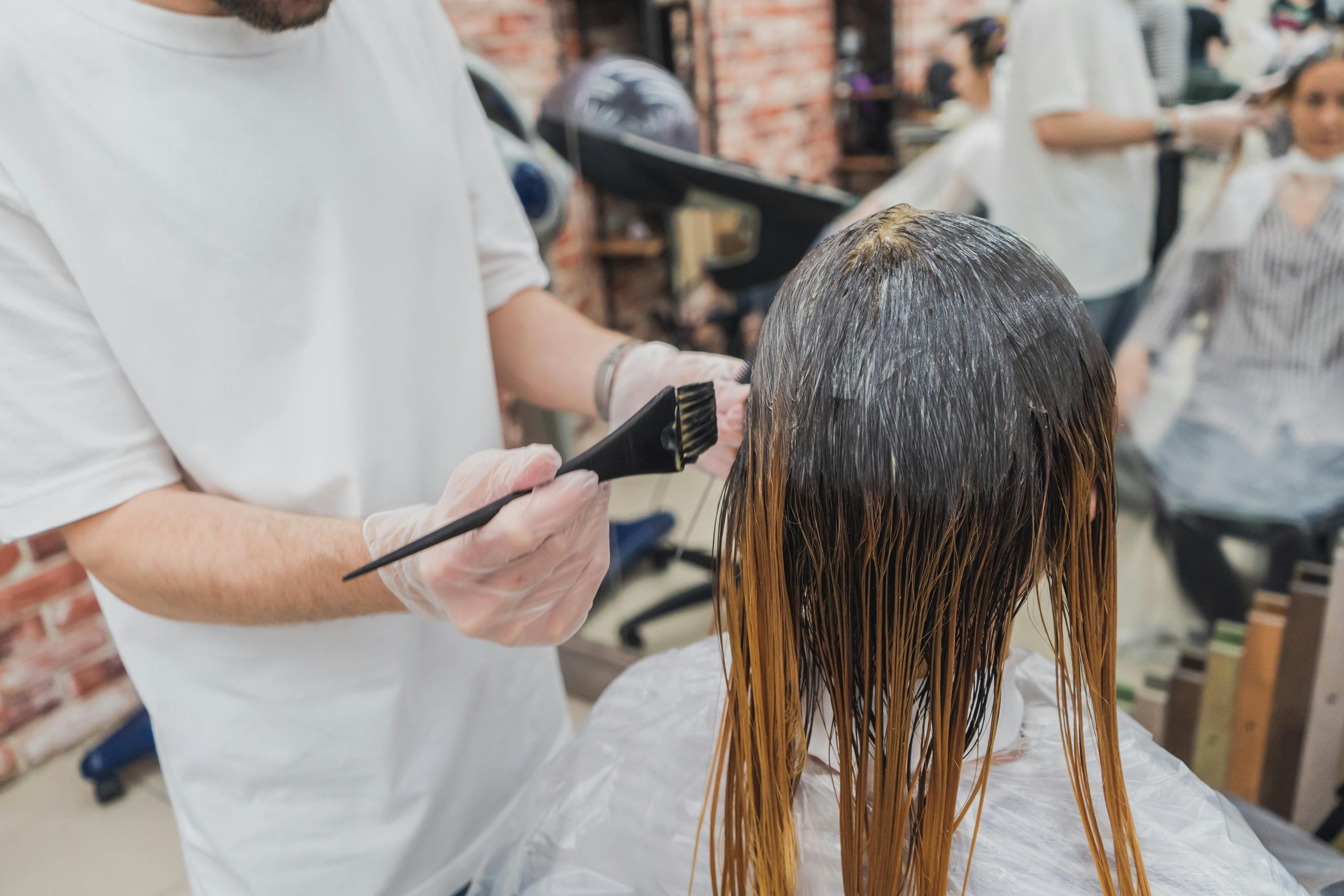 Professional stylist applying hair dye during a hair coloring service. This treatment showcases modern hair color ideas in 2024, with a focus on trendy new shades for the season.