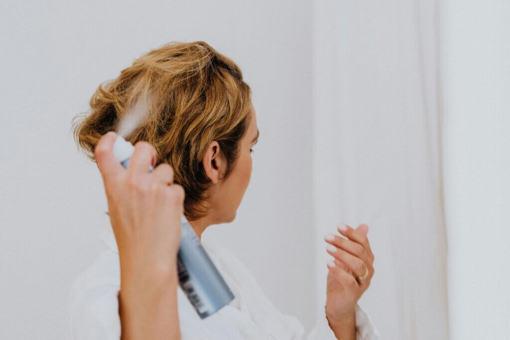 Woman using anti humidity hair products to style and protect their hair, keeping it smooth and frizz-free in humid conditions.