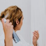 Woman using anti humidity hair products to style and protect their hair, keeping it smooth and frizz-free in humid conditions.