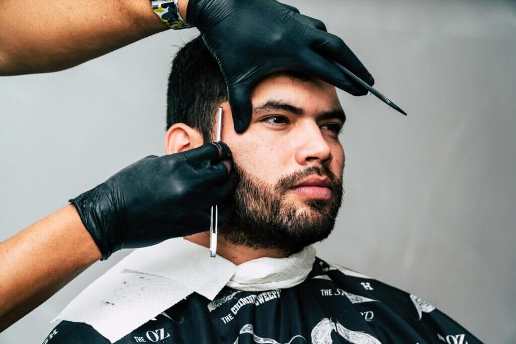 Close-up of a professional men's haircut in West Palm Beach, with a barber carefully shaping the client’s beard.