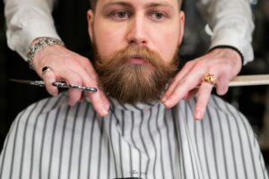Barber defining the edges of a full beard, creating a tailored grooming style.