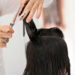 Close-up of a hairstylist cutting wet hair with scissors and comb, demonstrating how to cut short hair in a precise and professional way.
