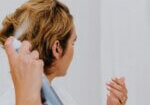 Woman using anti humidity hair products to style and protect their hair, keeping it smooth and frizz-free in humid conditions.