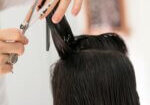 Close-up of a hairstylist cutting wet hair with scissors and comb, demonstrating how to cut short hair in a precise and professional way.