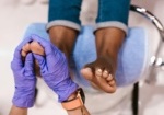 A close-up of a person receiving a professional pedicure in Palm Beach Gardens, with a focus on the foot massage being performed by a specialist wearing purple gloves.