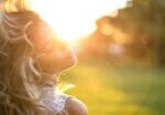 Golden sunlight shining through flowing blonde curls outdoors, highlighting potential UV damage to hair caused by prolonged sun exposure and dryness.