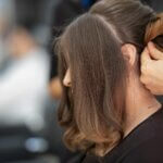 Close-up of a professional attaching hair extensions during a hair extension maintenance session