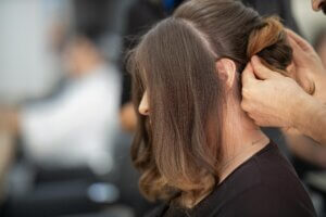 Close-up of a professional attaching hair extensions during a hair extension maintenance session