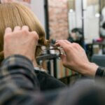 Stylist trimming a client’s hair during a consultation about what is the best hair style for different face shapes