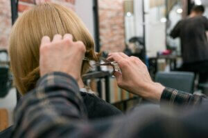 Stylist trimming a client’s hair during a consultation about what is the best hair style for different face shapes